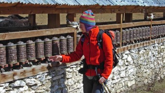 Trekker stoßt Gebetsmühlen bei der Annapurna Runde an.